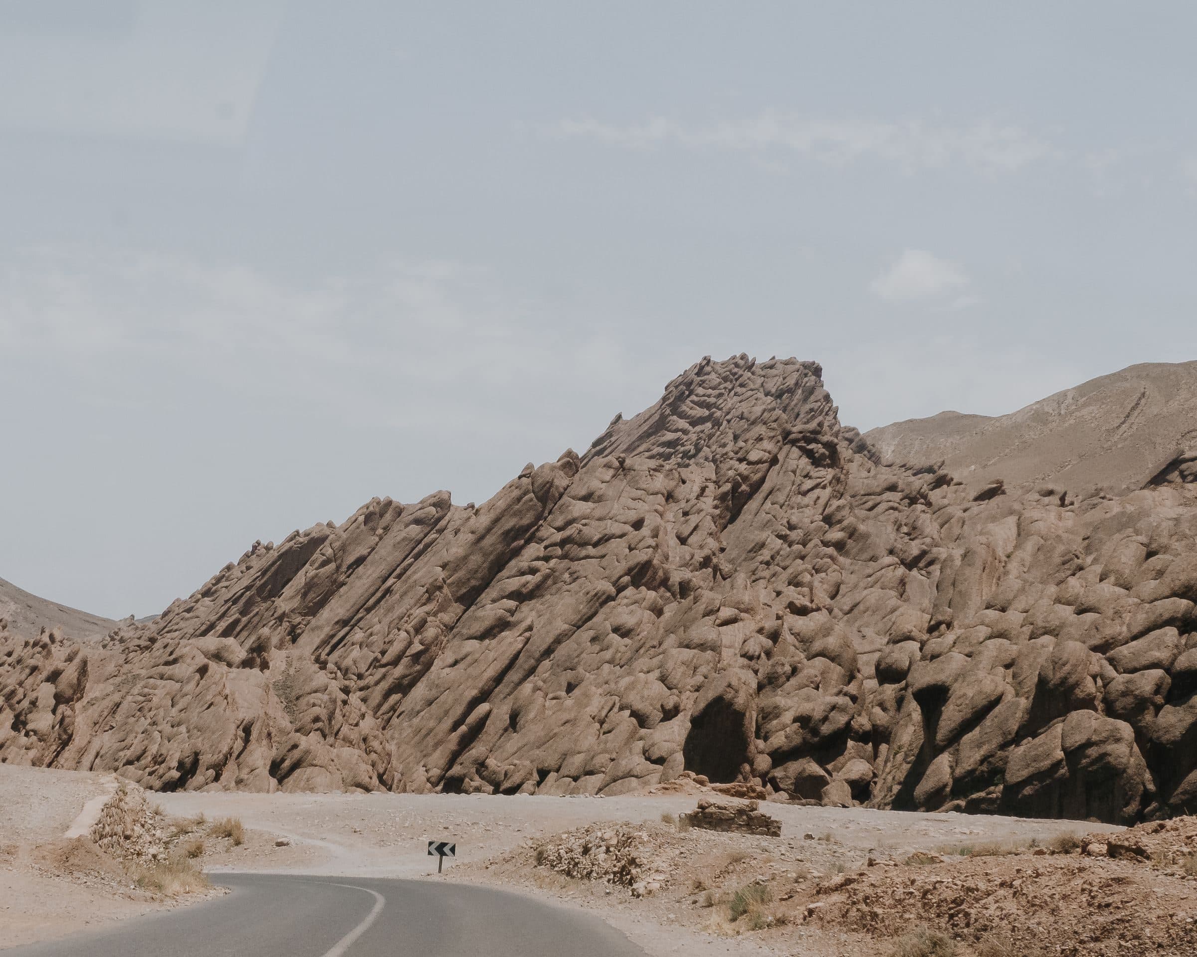 Empty road running alongside the rock formations of the Moroccan Atlas