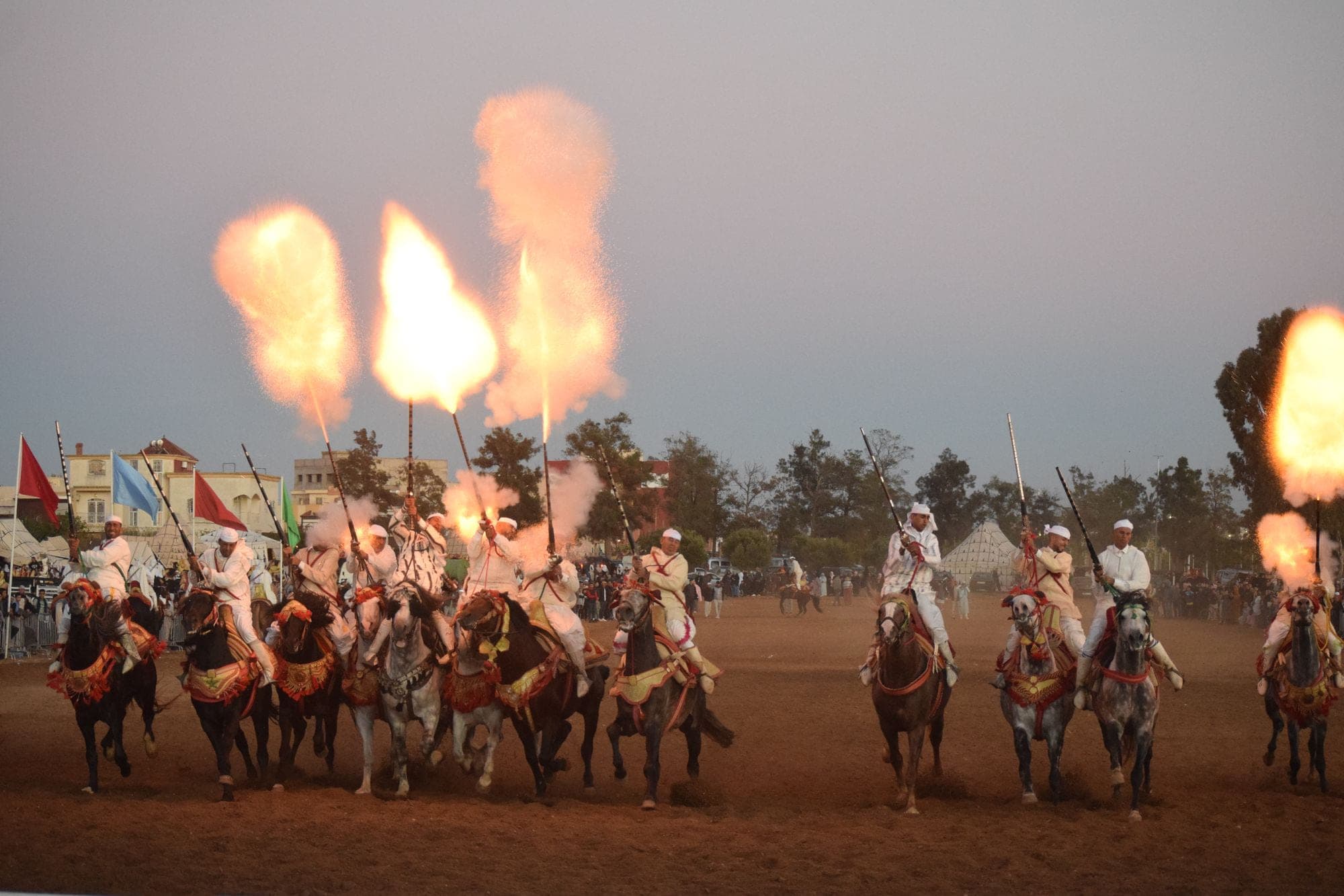 Moroccan horsemen in traditional dress performing a fantasia at dusk