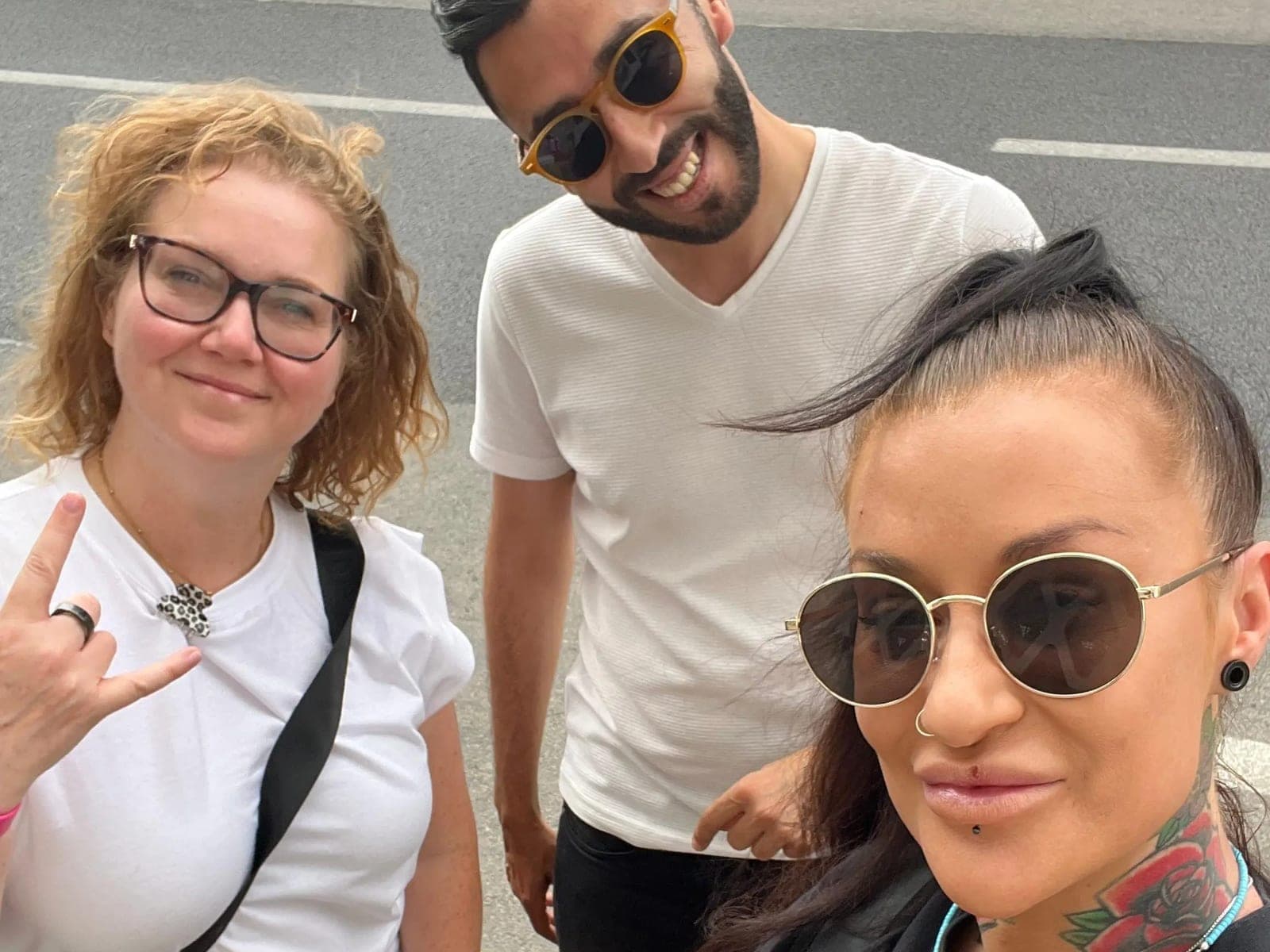 Two clients and their chauffeur smiling at the camera at the roadside meeting point