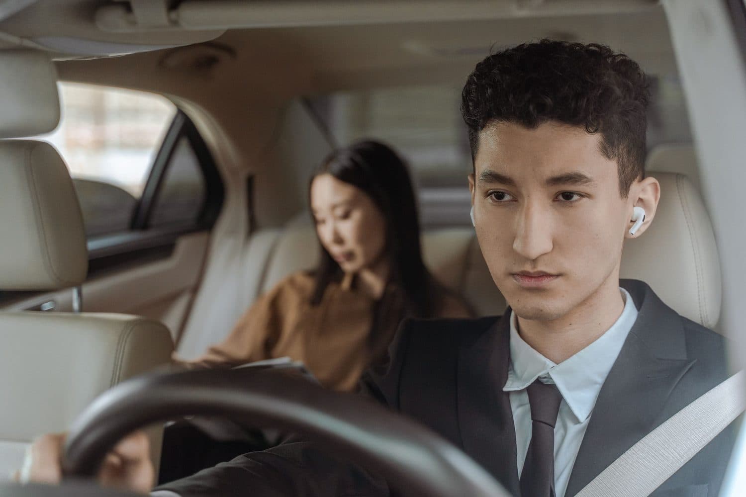 Chauffeur at the wheel with a passenger in the back, seen from inside the cabin
